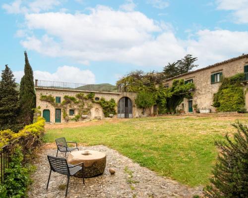 a stone building with two chairs and a table in a yard at Dependance a Baglio il Corvo by Wonderful Italy in Gangi