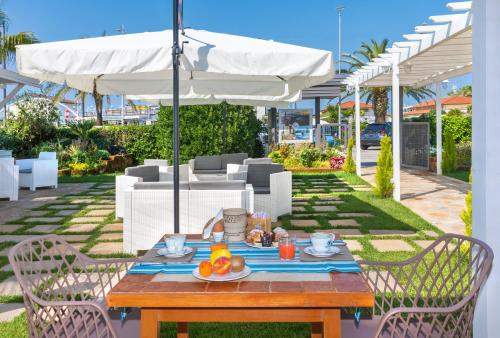 a wooden table with a plate of fruit and an umbrella at Hotel Siesta in Lido di Camaiore