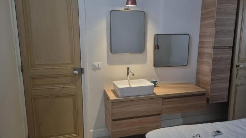 une salle de bain avec un lavabo et deux miroirs au mur dans l'établissement Maison Carnot, à Cannes