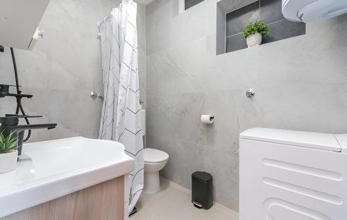 a white bathroom with a toilet and a sink at Apartmani Vanja in Drage