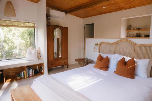 Un dormitorio con una gran cama blanca y una ventana en Treetop Tranquility, en Opua