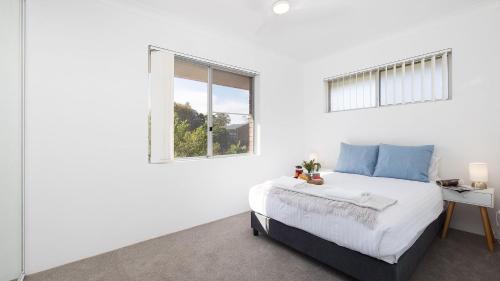 a white bedroom with a bed and a window at Beachside at Gretel in Nelson Bay