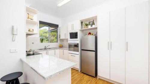 a kitchen with white cabinets and a refrigerator at Beachside at Gretel in Nelson Bay