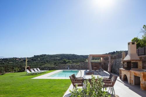 a backyard with a swimming pool and a patio with chairs at Villa Elides in Filakí