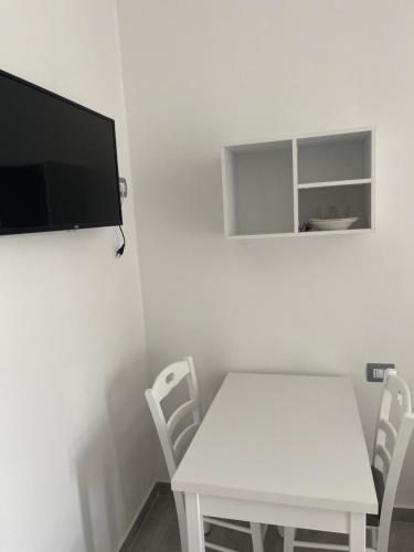 uma mesa branca e cadeiras com uma televisão na parede em LUMNIK - Hotel & Apartments em Lezhë