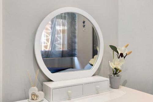 a mirror on top of a white dresser with flowers at Perla Marina Savona in Savona