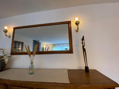 a table with a mirror and a vase on it at Grande maison avec jardin in Sarrancolin
