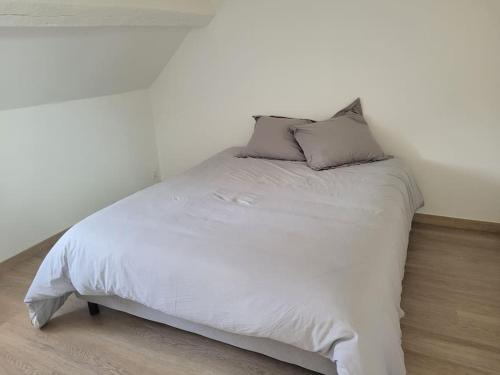 un lit blanc avec deux oreillers dessus dans l'établissement Appartement en duplex spacieux, à Colleville-Montgomery
