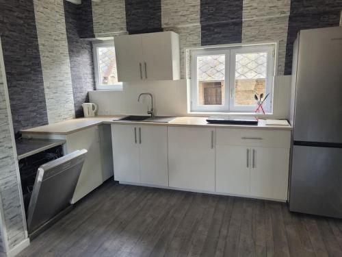 une cuisine avec des armoires blanches et un évier dans l'établissement Appartement en duplex spacieux, à Colleville-Montgomery
