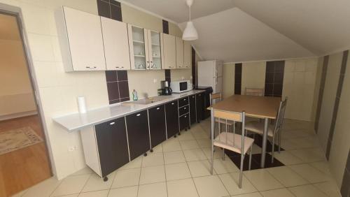 uma cozinha com armários brancos e uma mesa e cadeiras em Classic Apartament em Buzau