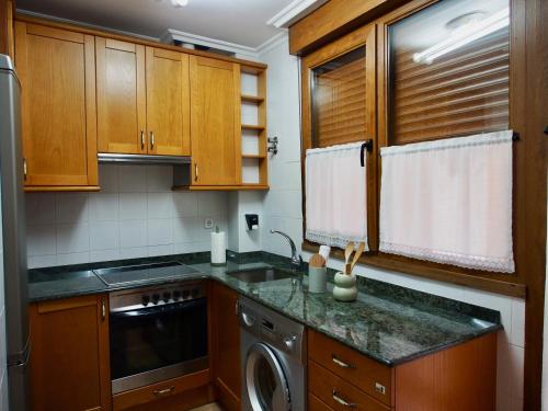 a kitchen with wooden cabinets and a dishwasher at Apartamentos Remoña 1 in Espinama