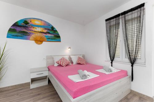 a white bedroom with a pink bed and a window at Apartman Biljana in Makarska