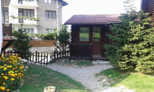 a small cabin with a fence next to a building at Guest House Raffe in Dobrinishte