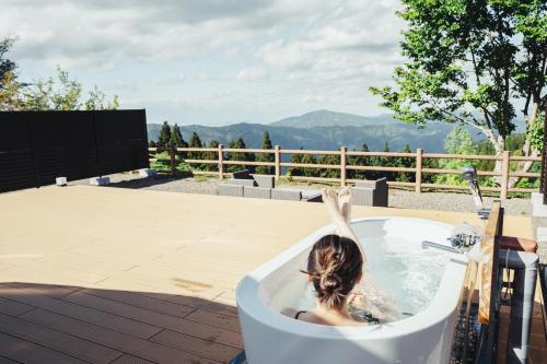 a woman in a bath tub with her arms up at LUONTE 霧の高原 Glamping in Dōnaru