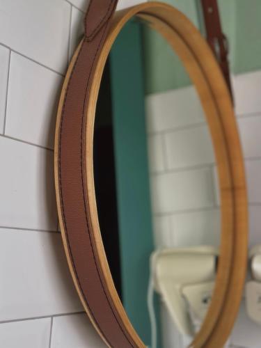 a wooden mirror hanging on a bathroom wall at Green Rooms in Kutaisi