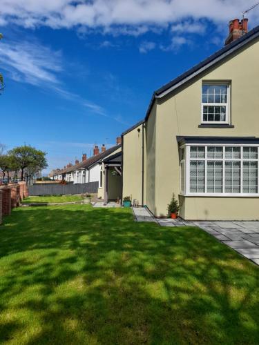 a house with a green lawn in front of it at Seaglass Cottage - Redcar in Redcar