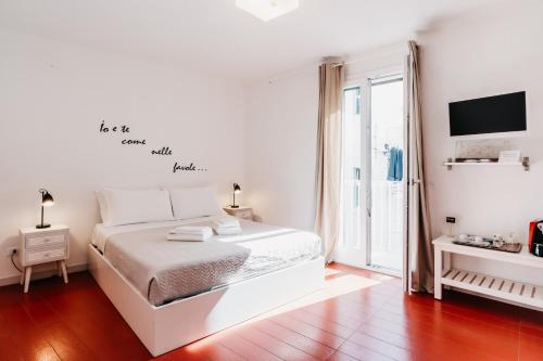 a white bedroom with a bed and a tv at Le Contrade Vico Alba in Monopoli