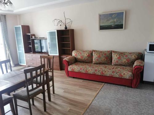 een woonkamer met een bank en een tafel en stoelen bij Neringa apartamentai in Palanga
