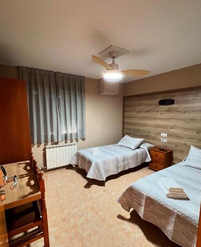 a bedroom with two beds and a ceiling fan at Hostal el secreto in Teruel