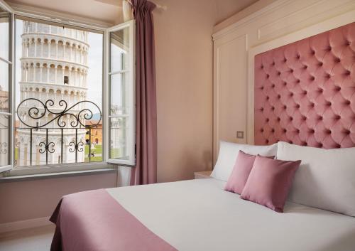 un letto con testiera rosa e una finestra con la torre pendente di Prato dei Miracoli Residenza d'Epoca a Pisa