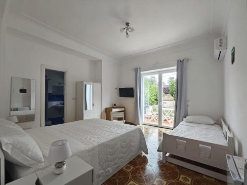 a white bedroom with two beds and a window at Casa Ferraro in Marina Grande di Capri