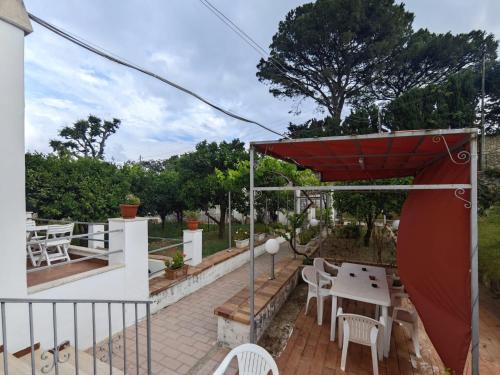 a patio with a table and chairs and a red umbrella at Casa Ferraro in Marina Grande