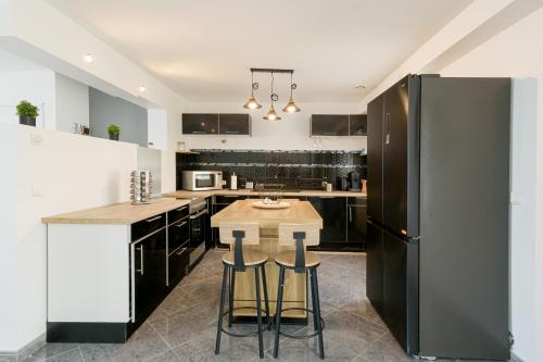 Il comprend une cuisine équipée d'un réfrigérateur noir et d'une table. dans l'établissement Le Havre Paisible - Belle maison proche de Paris, à Précy-sur-Marne