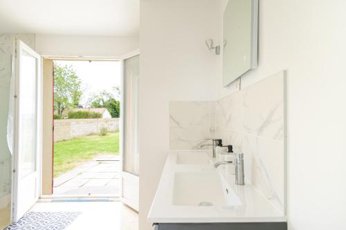 une salle de bain blanche avec un lavabo et une fenêtre dans l'établissement Le Havre Paisible - Belle maison proche de Paris, à Précy-sur-Marne