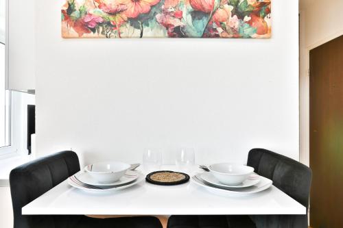 une table blanche avec deux chaises et un tableau sur le mur dans l'établissement Studio moderne - 3 Frontières - Aéroport de Bâle - Parking, à Saint-Louis