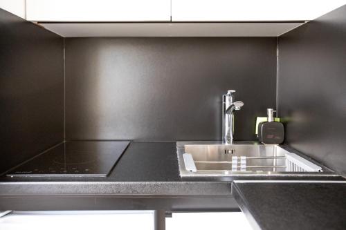 - une cuisine avec un évier et un mur noir dans l'établissement Studio moderne - 3 Frontières - Aéroport de Bâle - Parking, à Saint-Louis