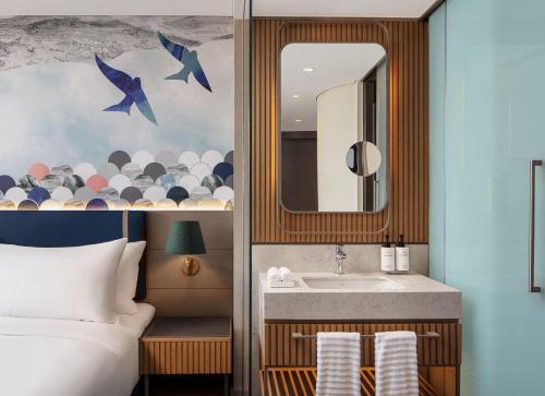 um quarto com uma cama, um lavatório e um espelho em Lokalist, Istanbul, a Tribute Portfolio Hotel em Istambul