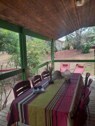 a table with pink chairs and a green and purple table cloth at Relais du Salagou - Chalets climatisés proche Lac du Salagou in Le Bosc