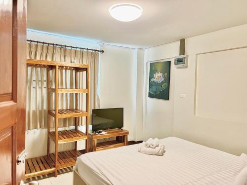 Dormitorio pequeño con cama y TV en Bloom Guesthouse, en Chiang Mai