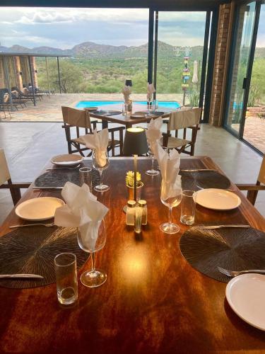 a wooden table with plates and wine glasses on it at Windhoek Game Camp in Lafrenz Township