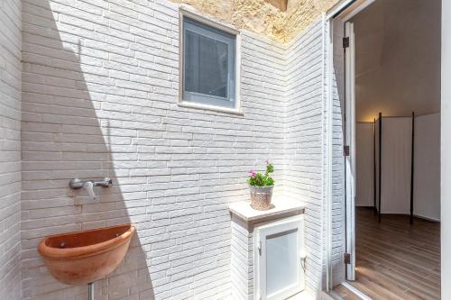 a bathroom with a wooden toilet in a white brick wall at San Biagio Apartment Lecce in Lecce