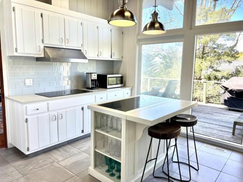 a kitchen with white cabinets and a counter with stools at Villa Perlman in Southampton