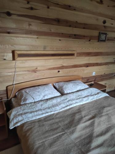 a bed in a room with a wooden wall at Vila VRABAC in Priboj