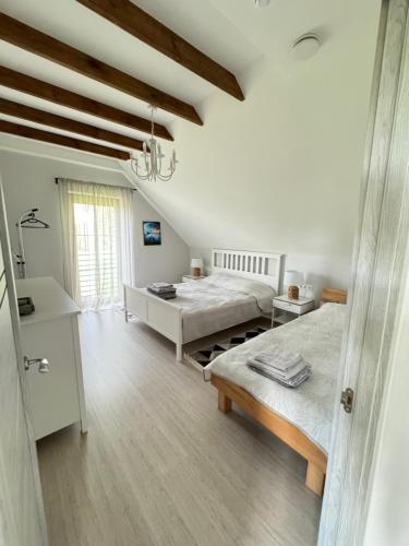 a white bedroom with two beds and a window at Seaside home Pape in Pape