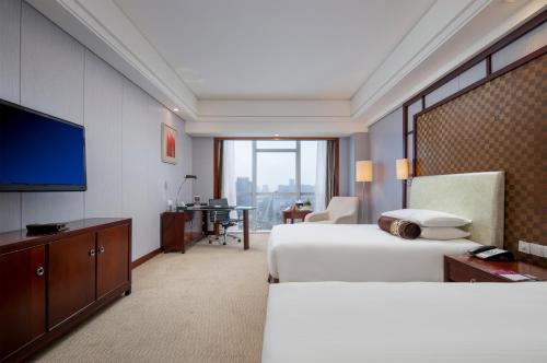 una camera d'albergo con due letti e una TV a schermo piatto di Haiwaihai Grand Hotel Ma'anshan a Ma'anshan