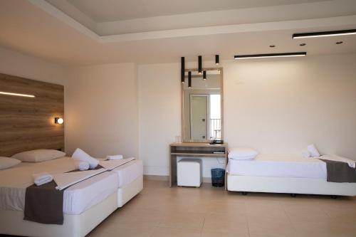 two beds in a room with a mirror and a sink at Dafni Plus Hotel in Leptokaria