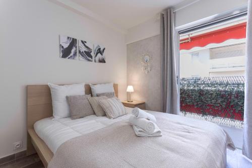 une chambre avec un grand lit blanc avec une fenêtre dans l'établissement Amandier du Moure Rouge, à Cannes