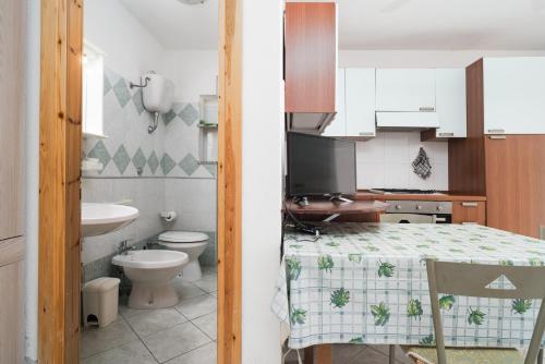 een keuken met een tafel, een toilet en een wastafel bij Monolocale San Giovanni Posada in San Giovanni