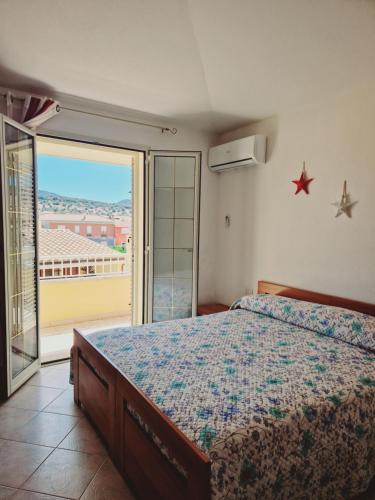 a bedroom with a bed and a balcony with a view at Affittacamere Sofy in Villasimius