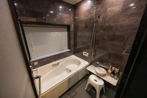a bathroom with a tub and a toilet and a sink at 箱根仙石原の宿 よいな in Hakone