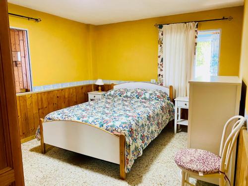 1 dormitorio con cama y pared amarilla en Casa El Potrero, en Mocanal