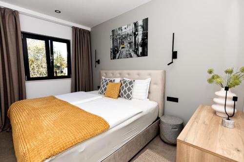a bedroom with a white bed with a yellow blanket at Villa Barovic - Premium apartment in Mlini
