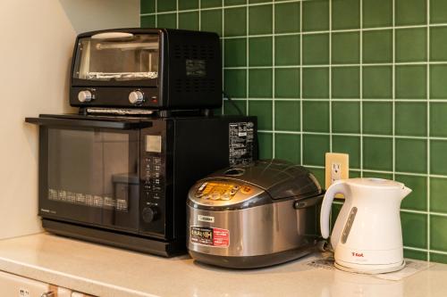a microwave and toaster oven on a kitchen counter at ペンション アネラニハウス沖縄 in Onna
