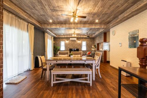 a dining room with a table and a ceiling fan at ペンション アネラニハウス沖縄 in Onna