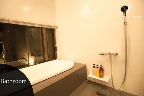 a bathroom with a tub and a shower with a window at -Musée Villa- in Nakijin
