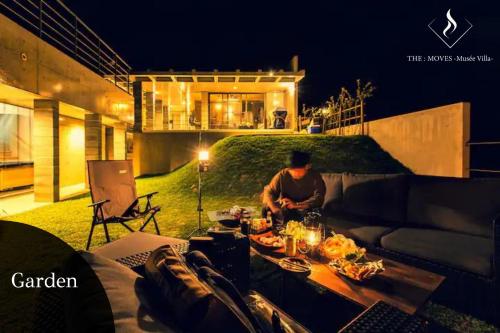 a man preparing food on a table in a backyard at -Musée Villa- in Nakijin